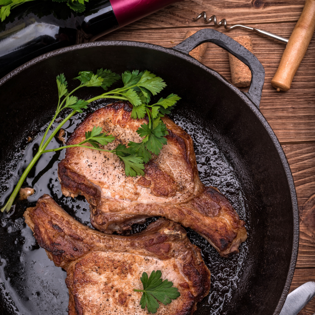 BBQ porkchops in a cast iron pan with a bottle of red wine