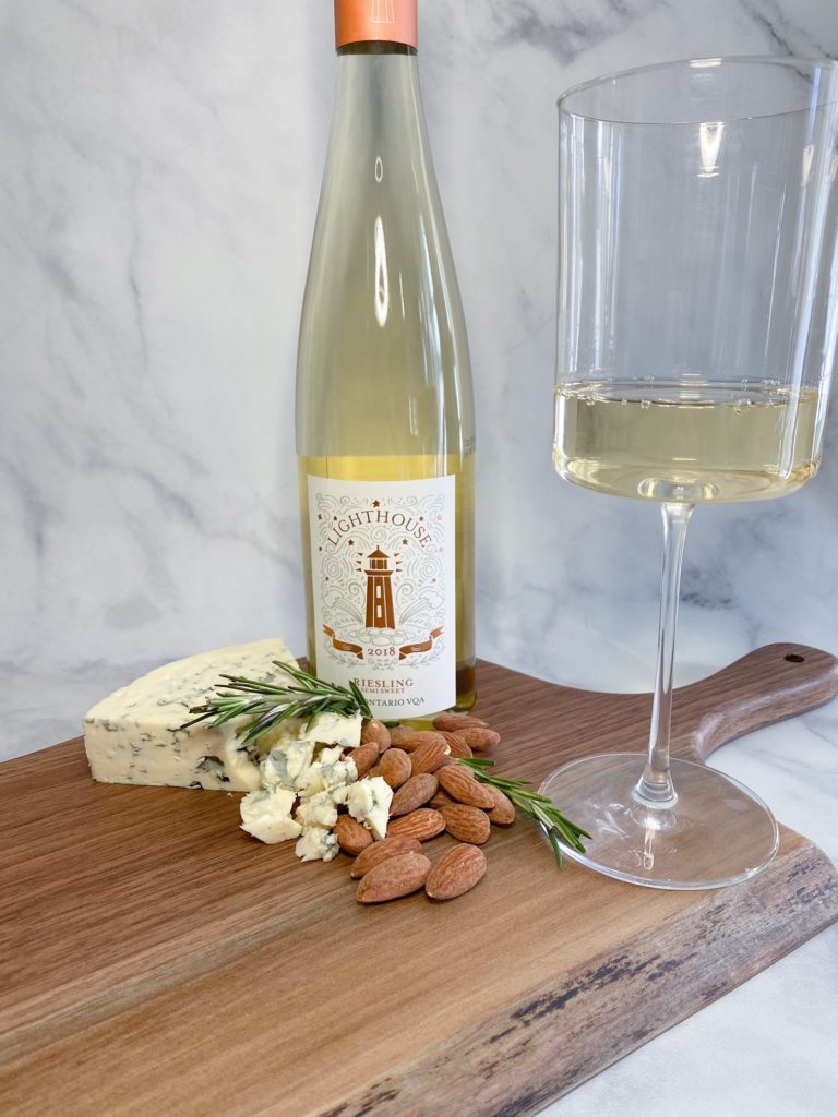 Pelee Island Winery Lighthouse Semi-Sweet Riesling VQA on ConVino charcuterie board with white wine glass, almonds and blue cheese with sprig of rosemary